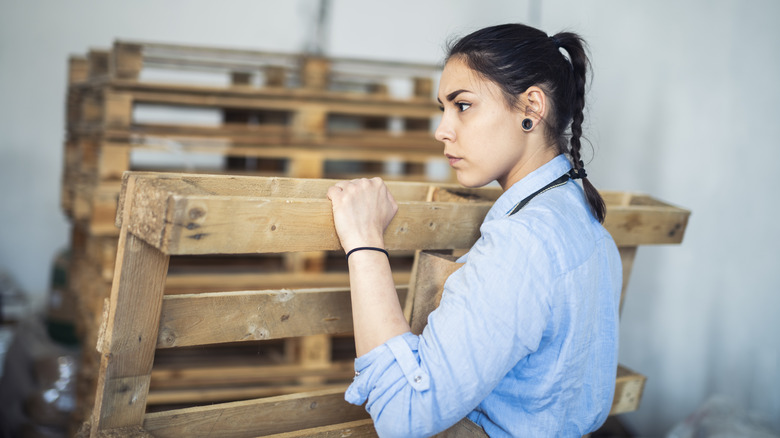 Woman carrying wood pallets