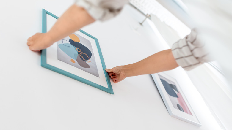 Person removing green-framed picture from wall.