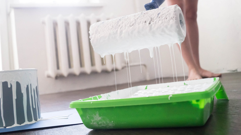 Person holding dripping paint roller