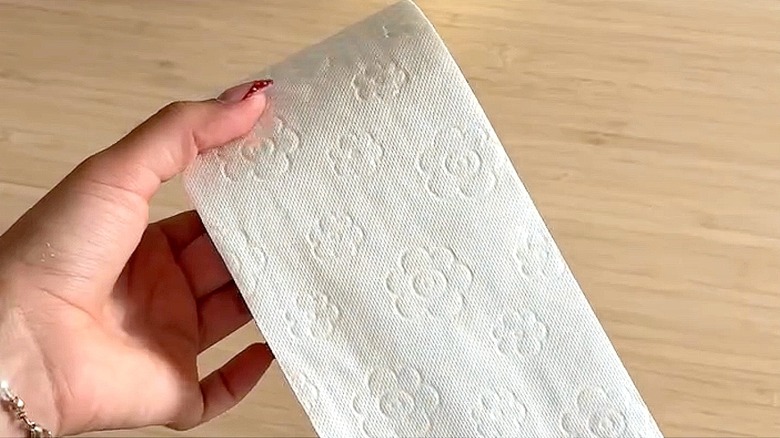 Close-up of a person rolling out tissue from a toilet paper roll for a craft
