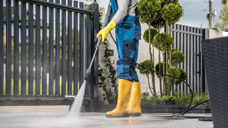 A person pressure washes a driveway