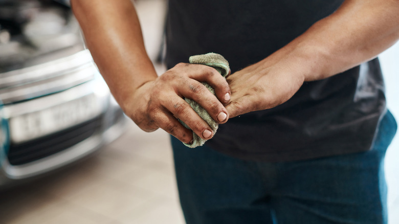 Man wiping hands clean with towel in garage