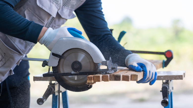 A man cutting lumber using a circular saw
