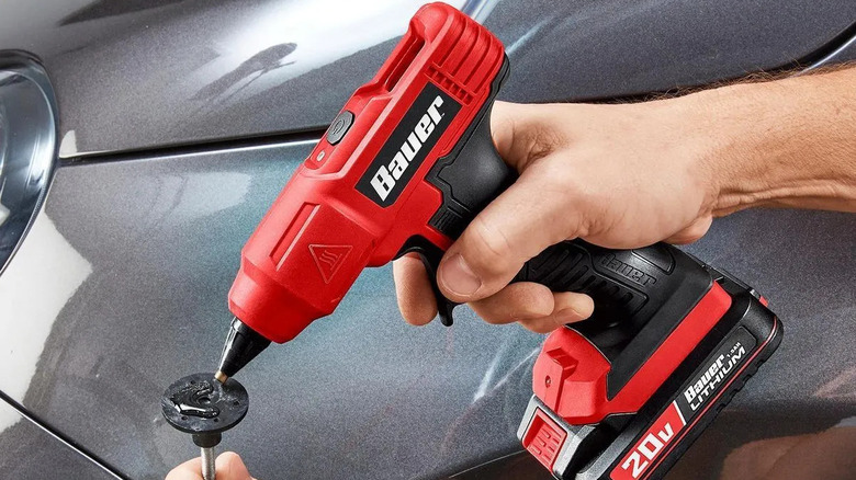 Person using BAUER 20V Cordless Glue Gun to fix car part