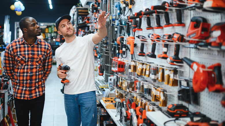 Men shopping for drills in hardware store