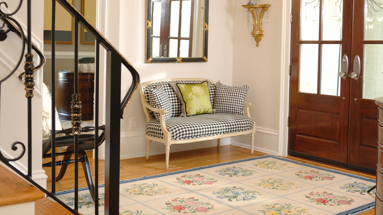 Luxurious home with cushioned seating, staircase, wooden front doors, and floral rug