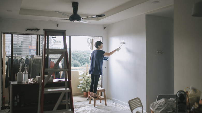 Person painting wall with light reflecting on wall.