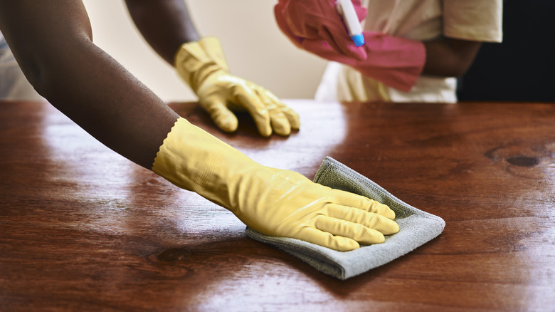 Gloved hand cleans wood surface