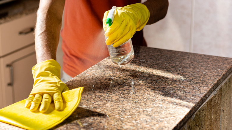 person wiping granite countertop