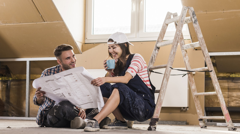 Couple looking at blueprints or plans in unfinished attic