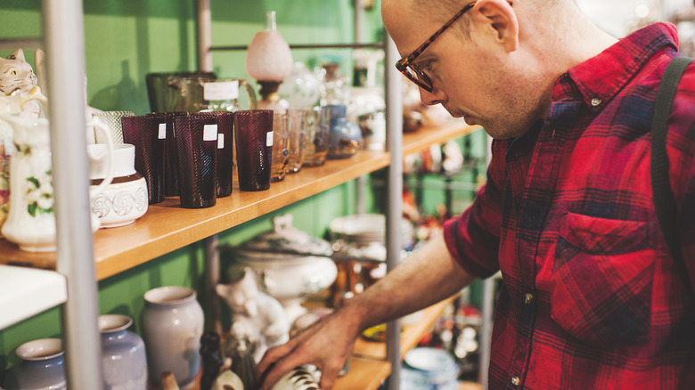 A man is shopping for glassware at a thrift store