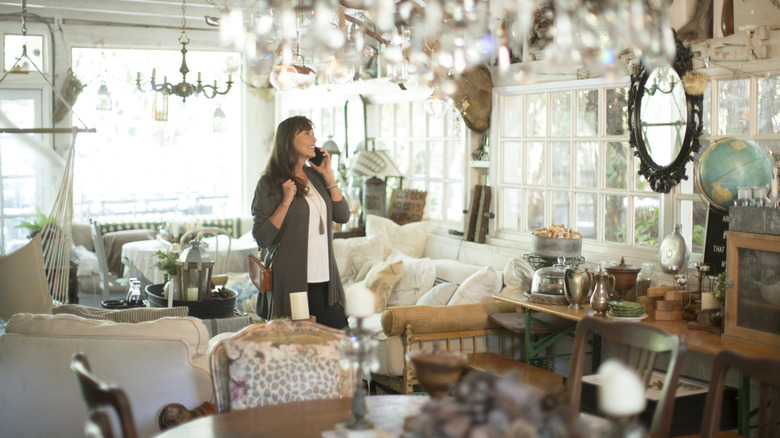 A woman looks at the chairs in an antique store