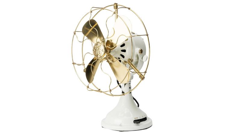 A white industrial fan with brass blades.