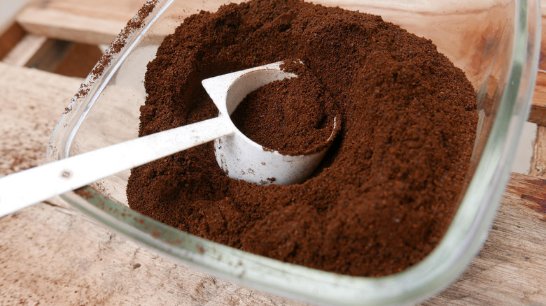 A close up of a bowl of coffee grounds with a scoop