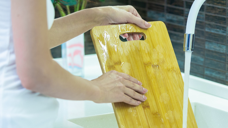 Woman cleans off a cutting board