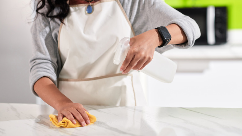 Woman cleaning counter with a spray bottle and cloth