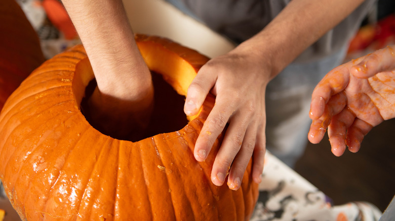 Hand scooping out pumpkin for carving
