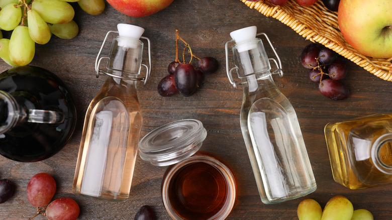 Vinegar and apple cider vinegar in glass bottles on a table with fruits