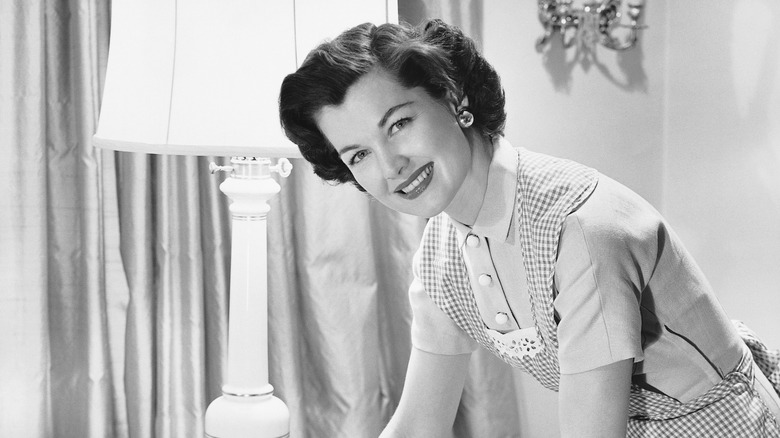A vintage photo of a woman wiping a table in an apron