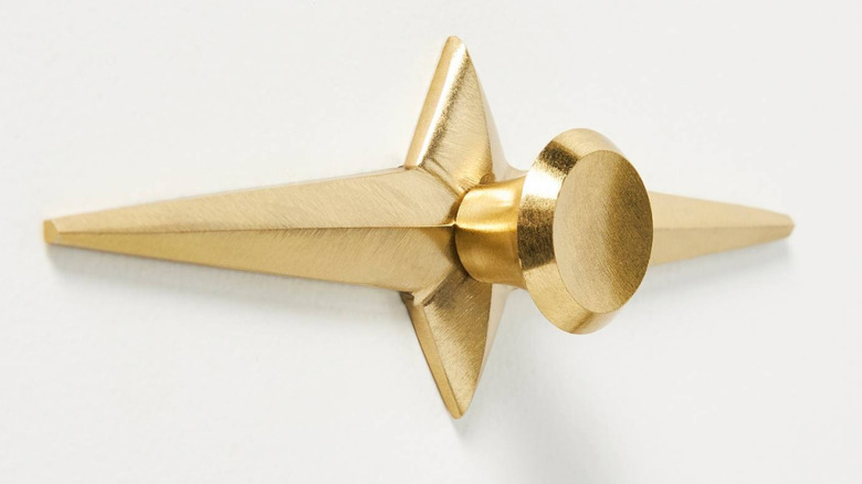 A gold starburst drawer pull against white,