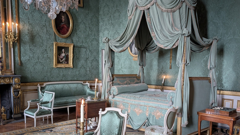 Vintage Parisian bedroom with turquoise wallpaper and canopy bed.