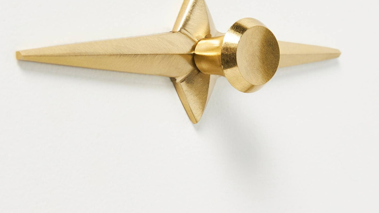 A gold starburst drawer pull against white,