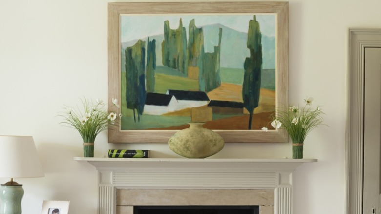 Landscape painting by Jeremy Fraser above chimney piece in bedroom with wool checked throw