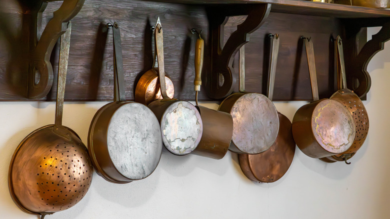 vintage pot rack on a wall with copper cookware hanging