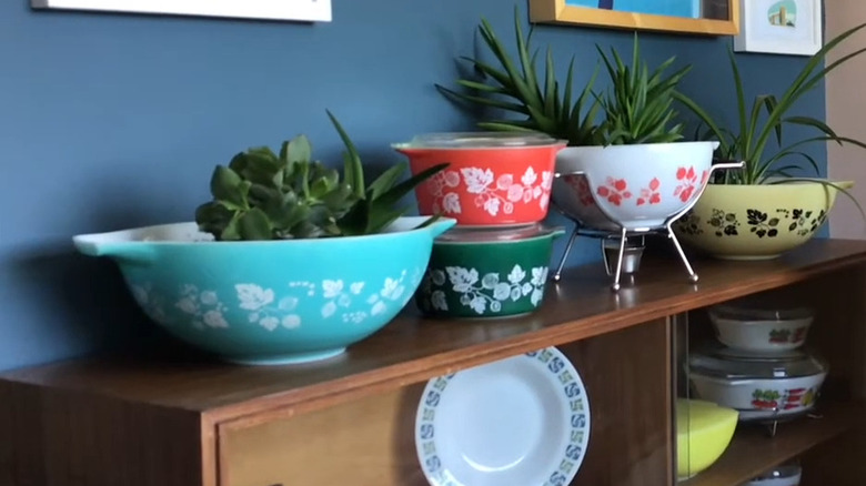 Collection of colorful vintage Pyrex bowls used as planters