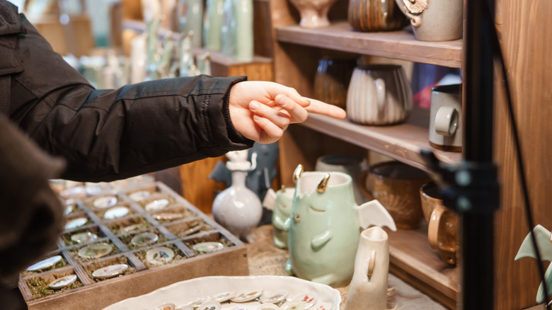 Assorted plates, mugs, and bowls on metal thrift store shelf.