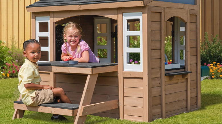 Two kids playing in the KidKraft Sunny Bluff Playhouse
