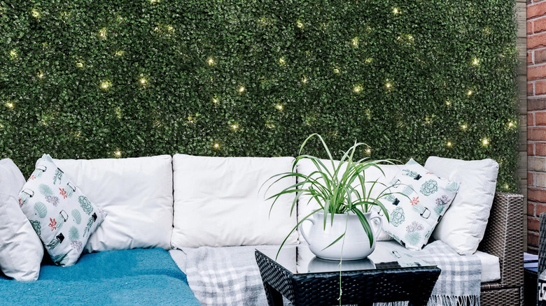 Golden Select artificial hedge hanging behind patio set in a yard