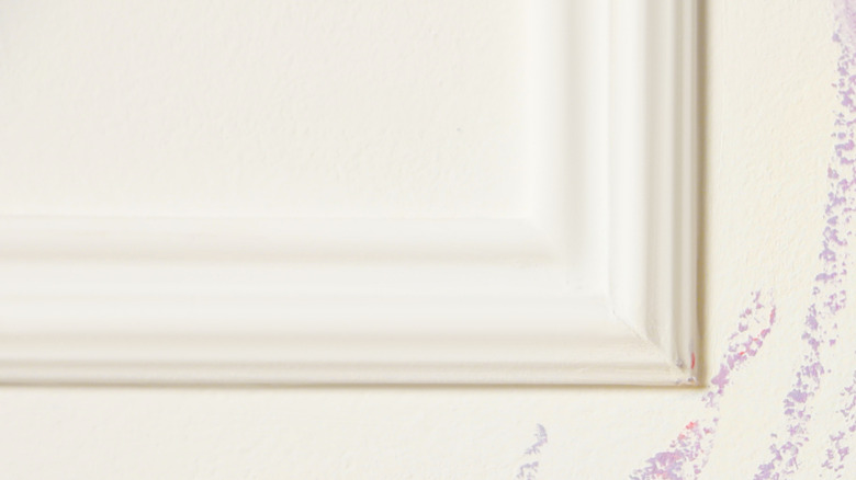 Close-up of a person cleaning crayon off of a wall