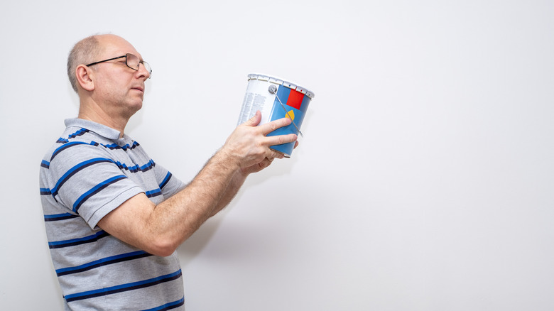 A person reading the instructions on the back of a paint can