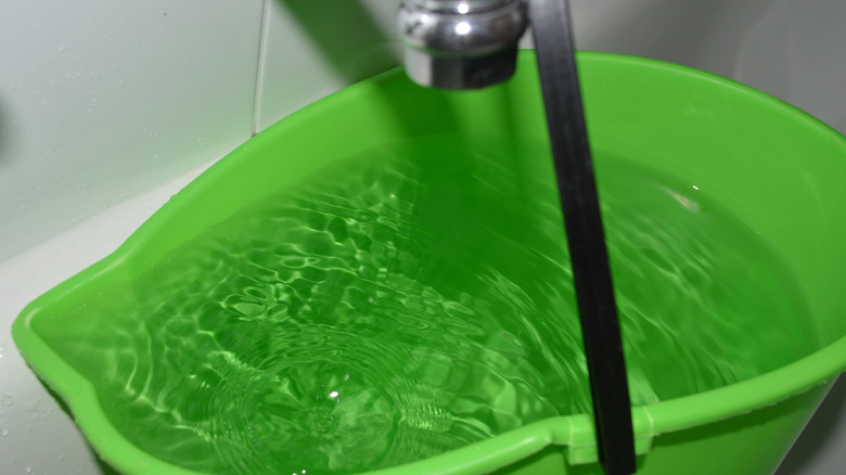 Bucket of water being filled in a bath tub