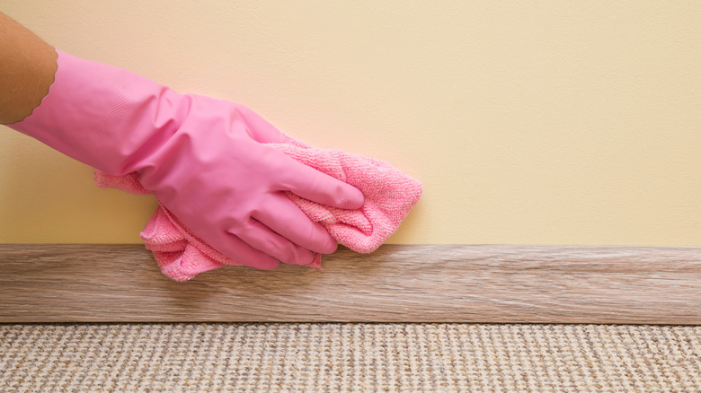 Close-up of a gloved hand wiping a painted wall with a soft cloth