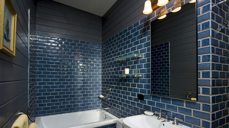 A bathroom with navy tiled walls