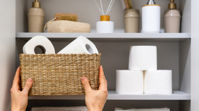 Hand organizing a bathroom cabinet with a basket