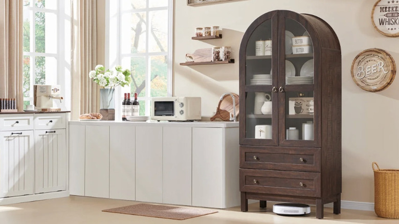 A brown tall, arched storage cabinet in a kitchen