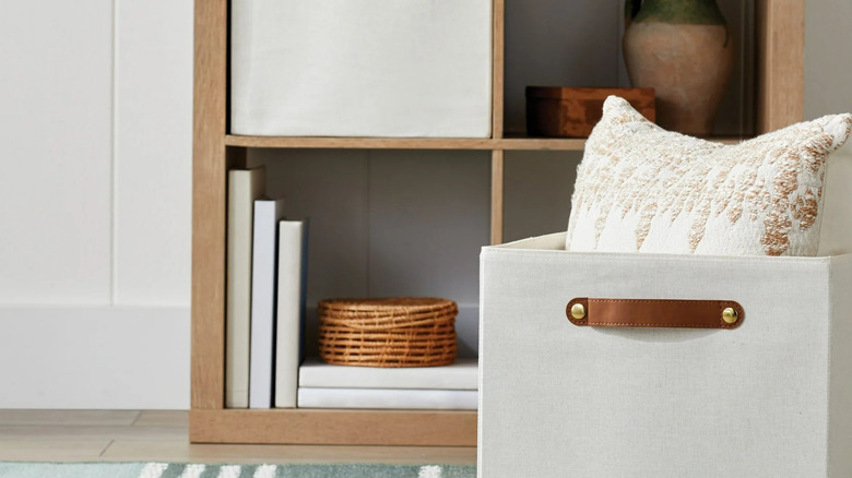 A light storage cube with a leather handle sits in front of a small bookshelf