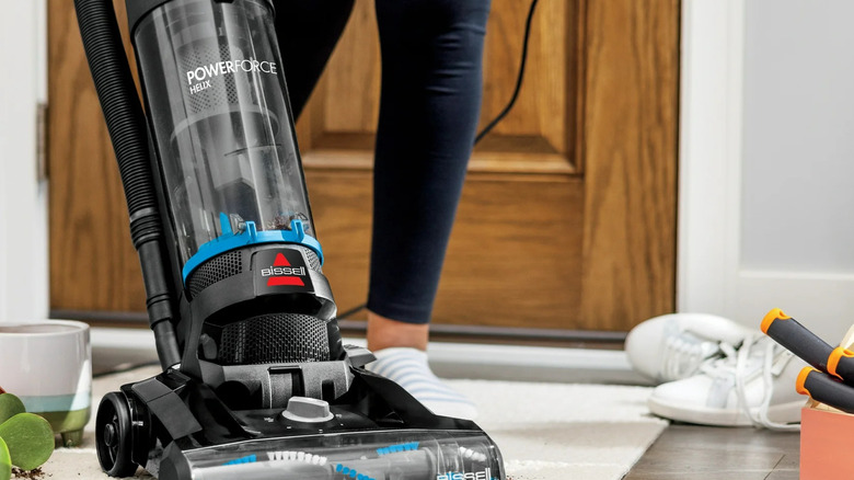 A Bissell Upright Powerforce Helix Vacuum is used to clean up dirt on a white rug