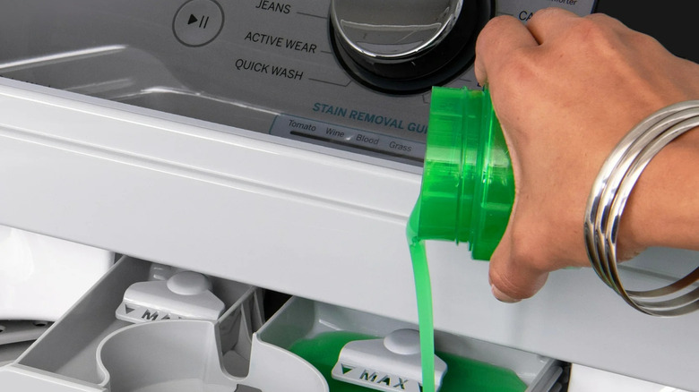 A woman wearing silver bangles pours Gain liquid detergent into a washing machine