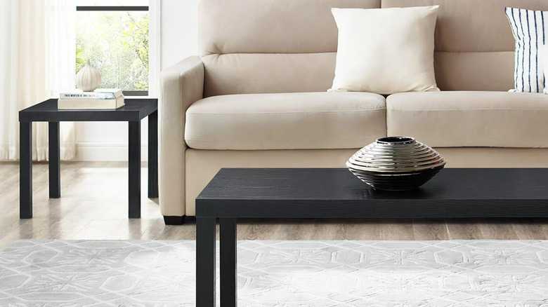 A black Parsons coffee table sits in front of a beige sectional sofa
