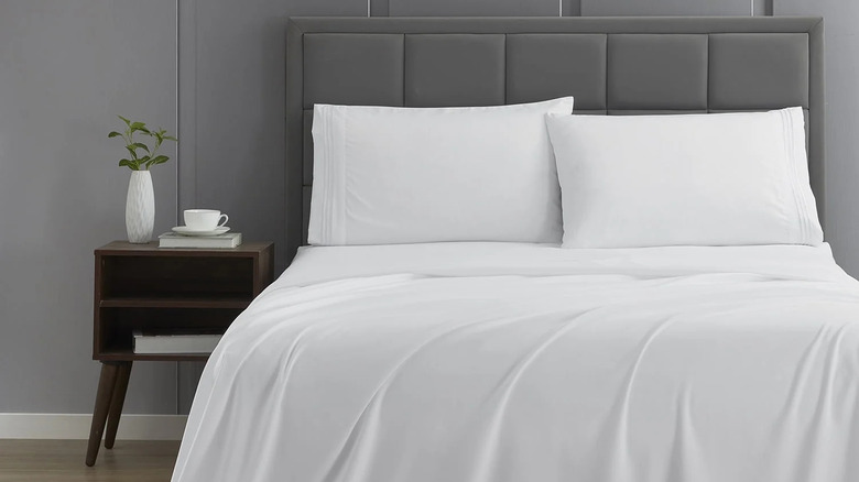 A bed is made with white Nestl sheets