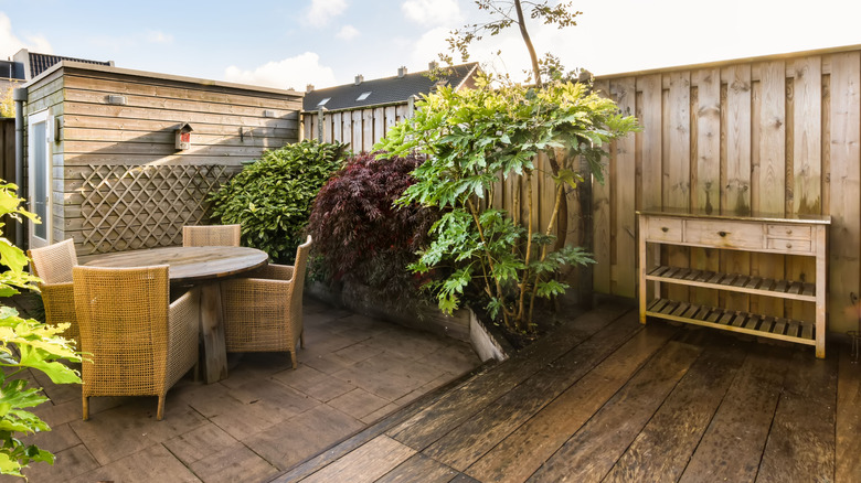 A backyard patio with a storage cabinet and a wicker dining table set