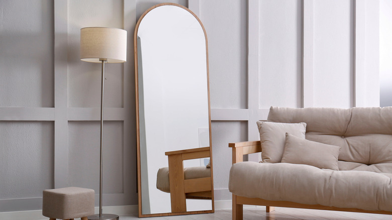 A golden arched mirror in a minimalist living room.