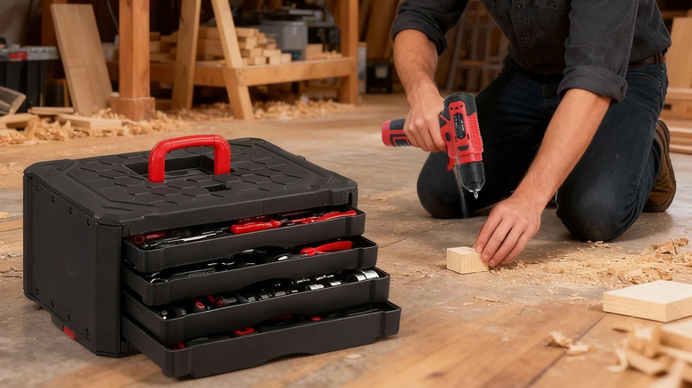 A man kneels in a woodworking shop next to a large black tool set