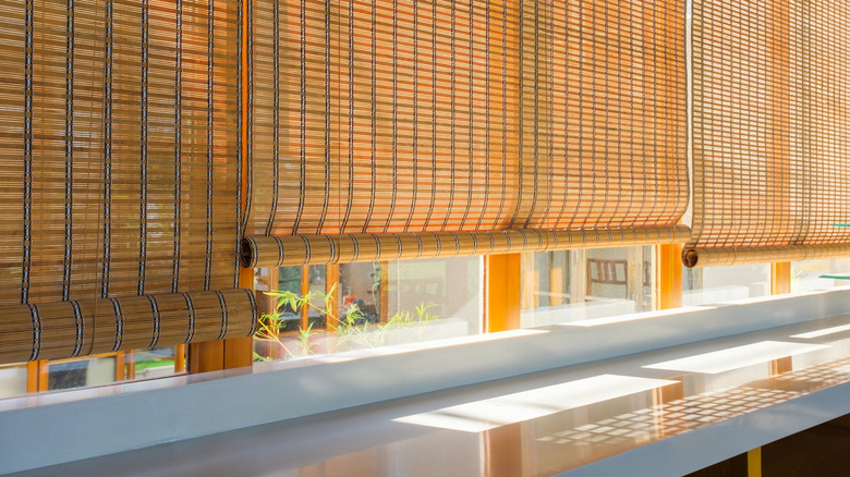 Bamboo blinds partially block the sun on a wall of windows.