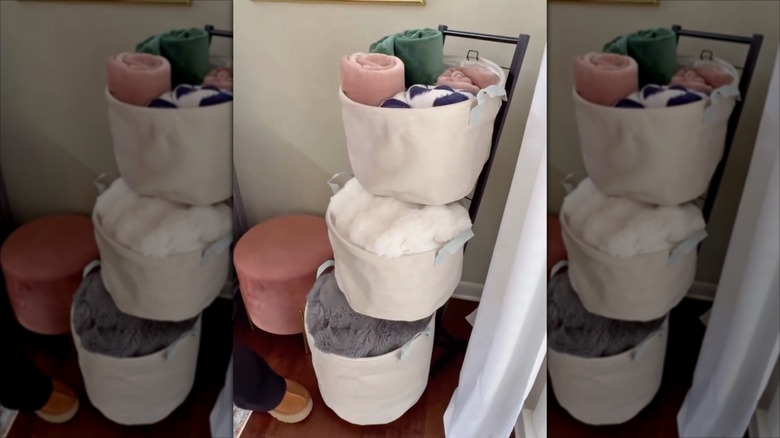 a three-tier hamper used to store blankets in a living room