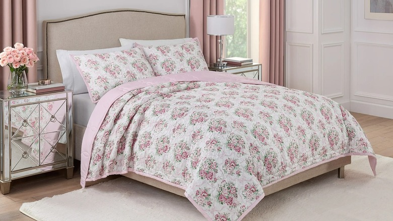 Pink floral quilt on a bed in a light-colored bedroom